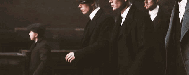 a group of men in suits and hats are standing in a line