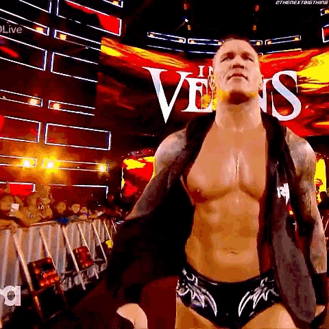 a shirtless wrestler is standing in front of a large screen with the word venus written on it .