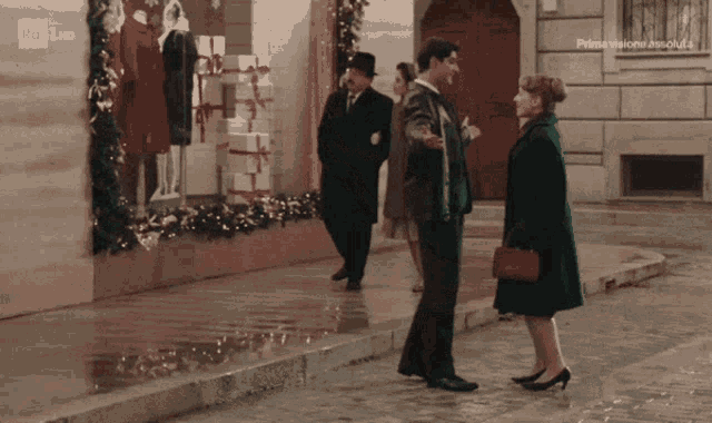 a woman in a green coat is standing next to a man in a top hat in front of a store window that says rai