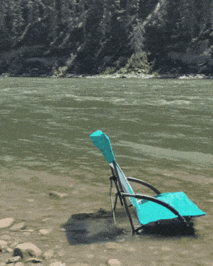 a blue chair sits in the water near the river