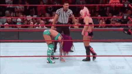 two women are wrestling in a ring with a referee .