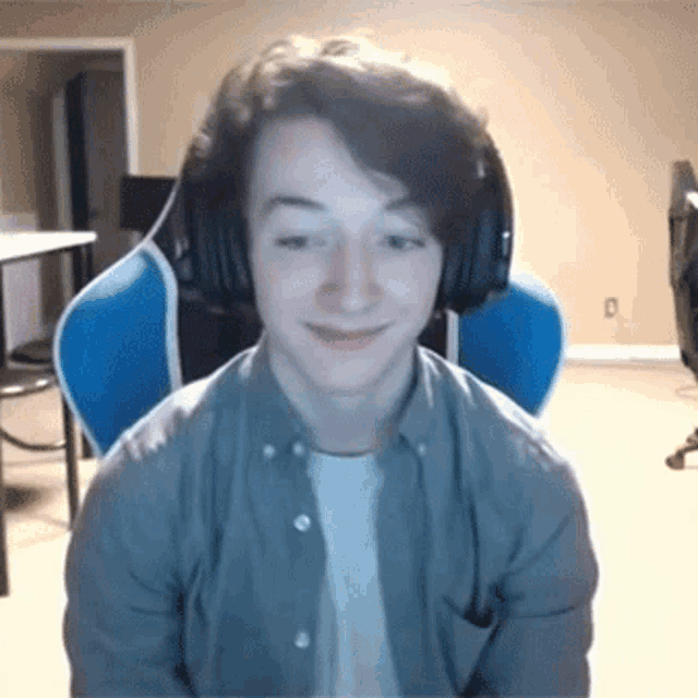 a young man is wearing headphones and smiling while sitting in a chair .