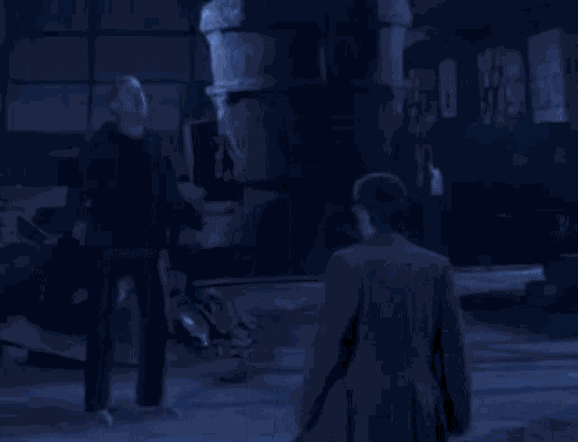 a group of people are walking in a dark room with blue lights coming out of the ceiling .