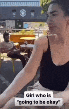 a woman in a black tank top is sitting at a table with a man sitting at a table .