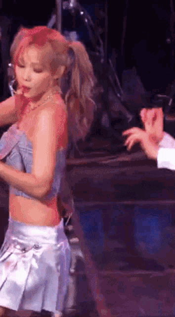 a woman in a crop top and white skirt is dancing on stage