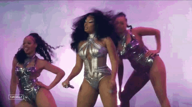 a woman in a silver swimsuit is dancing with two other women