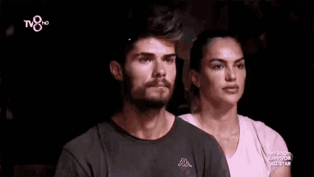 a man wearing a kappa shirt stands next to a woman in a pink shirt