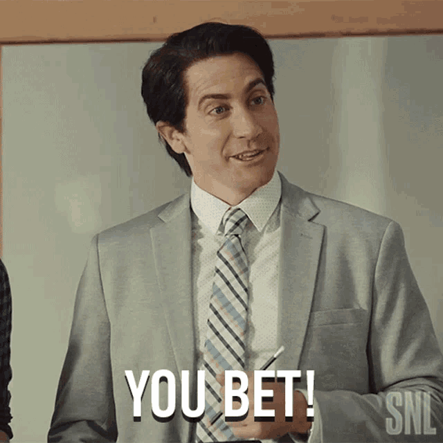 a man in a suit and tie says " you bet " in front of a white board