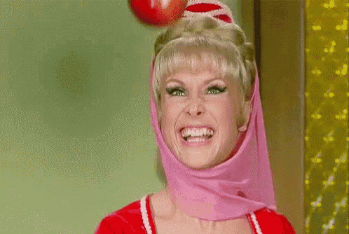 a woman wearing a pink dress and a red hat is smiling and waving .