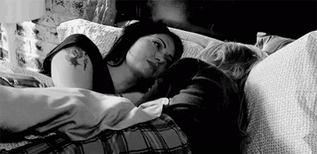 a black and white photo of a couple laying in bed .