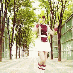 a woman in a red and white outfit is walking down a sidewalk surrounded by trees .