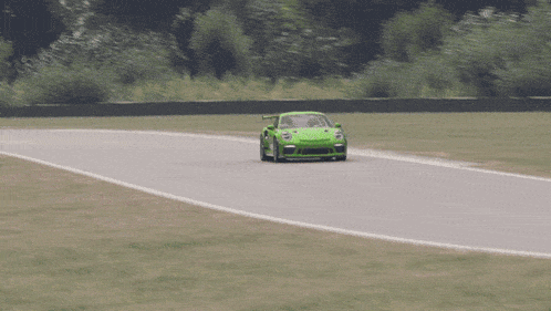a green porsche is driving down a track