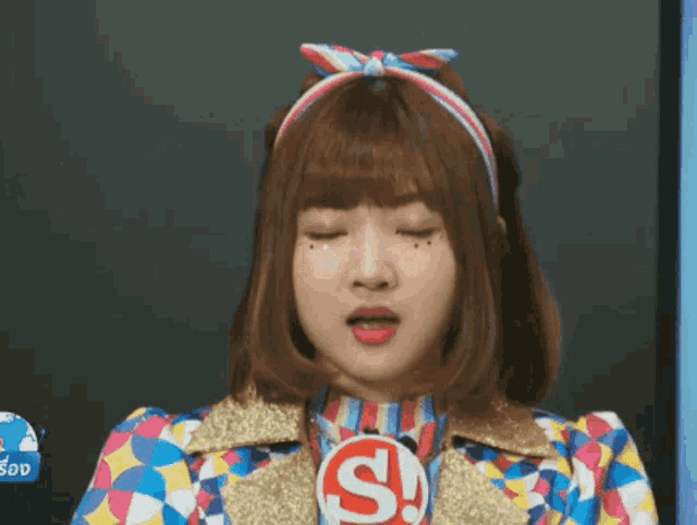 a girl in a colorful outfit says ohh baby in front of a blackboard