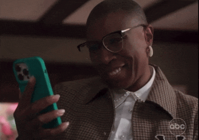 a woman wearing glasses is smiling while holding a cell phone