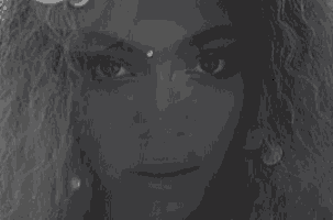 a close up of a woman 's face in a black and white photo with a flower in her hair .