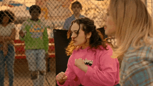a woman in a pink sweatshirt with the word albert on it is standing next to another woman