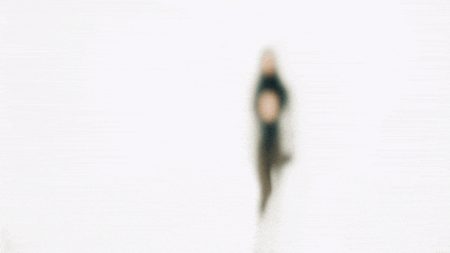 a blurred image of a woman dancing in front of a white background .