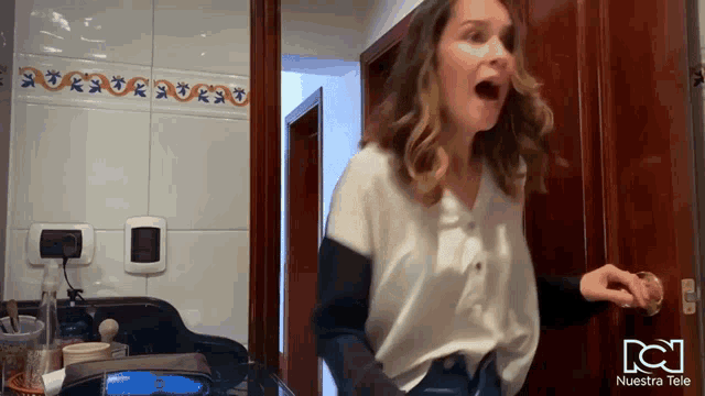 a woman standing in a bathroom with nuestra tele written on the bottom right