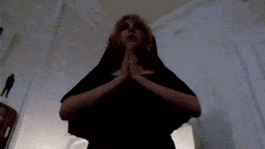 a woman in a nun costume is praying with her hands together