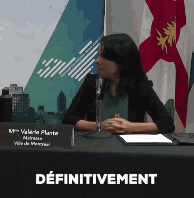 a woman sitting at a table with a sign that says mme valerie plante