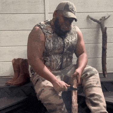 a man in a camo vest is cutting a log