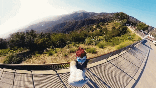 a woman taking a picture of herself on a balcony overlooking a mountain