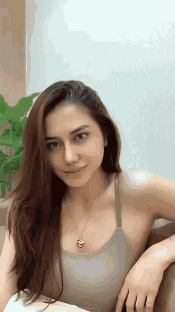 a woman in a tank top with a heart shaped necklace