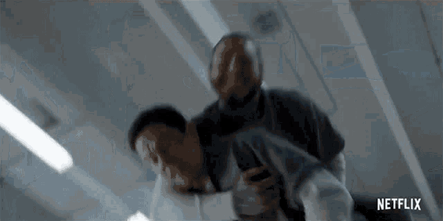 a man is holding another man in his arms while they are fighting .