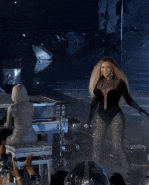 a woman in a black bodysuit sings into a microphone on a stage