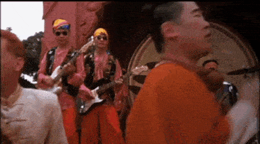 a group of men are playing guitars in front of a crowd of people .