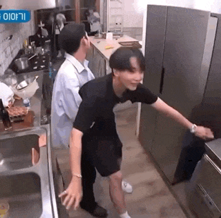 two men are standing in a kitchen next to each other .