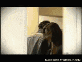 a man and a woman are kissing behind a door ..