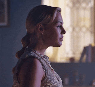 a woman wearing a ponytail and earrings looks to the side