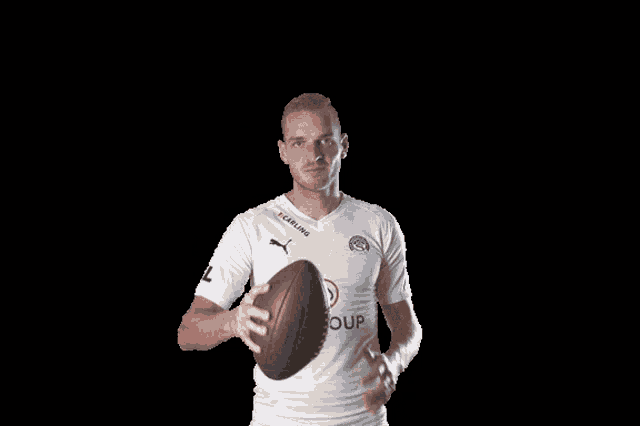 a man in a white z-group shirt is holding a football