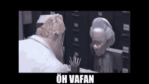 a man and an older woman are sitting at a desk with the words oh vafan on the bottom .