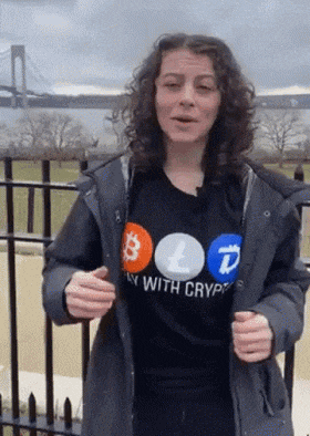 a woman wearing a shirt that says " play with crypto " is standing in front of a bridge