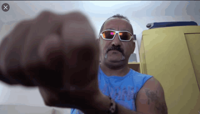 a man wearing sunglasses and a blue tank top has a tattoo on his arm that says ' i love you '