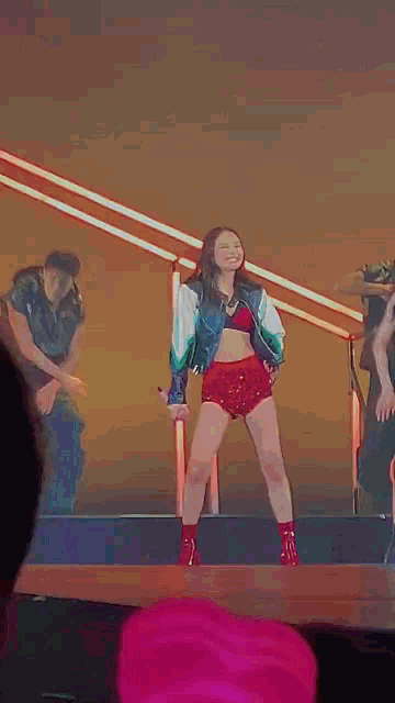 a woman in red shorts is dancing on a stage