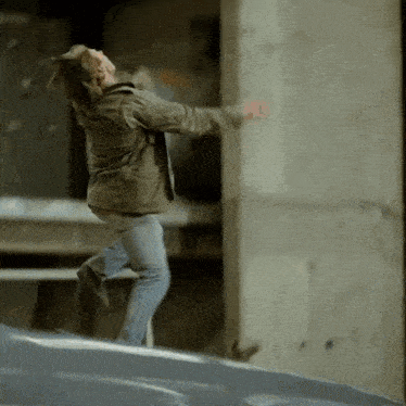 a man in a jacket is jumping in the air with his arms outstretched