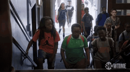a group of children are walking down stairs in a hallway with showtime written on the bottom of the screen .