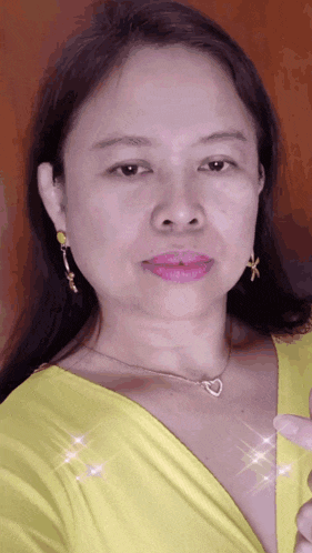a woman wearing a yellow shirt and a heart shaped necklace