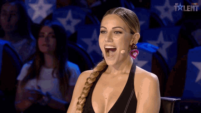 a woman wearing a braided ponytail is sitting in front of a microphone in front of a screen that says talent