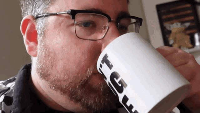 a man wearing glasses is drinking from a mug that says i 'm a giant
