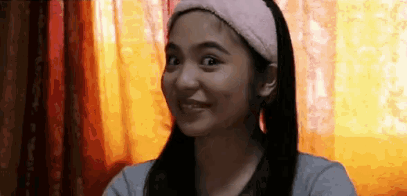 a woman wearing a pink headband is smiling in front of a window