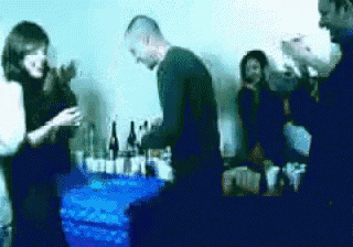 a group of people standing around a table with bottles of alcohol