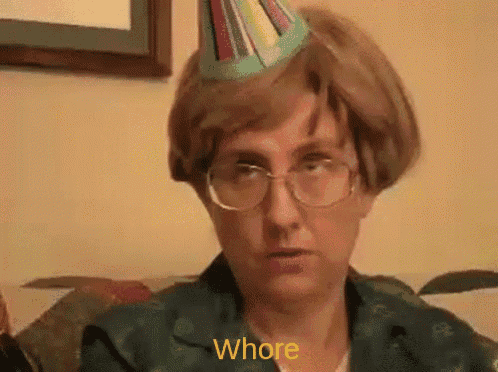 a woman wearing glasses and a party hat is sitting on a couch and saying whore