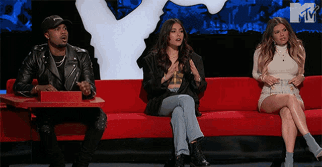 a group of people sitting on a red couch with a mtv logo behind them