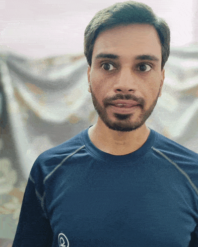 a man with a beard is wearing a blue shirt with the letter o on it