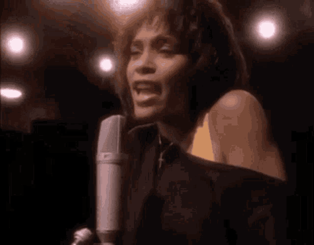 a woman is singing into a microphone on stage .