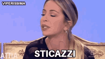 a woman is sitting in a chair with her eyes closed and the words sticazzi written on the screen behind her .